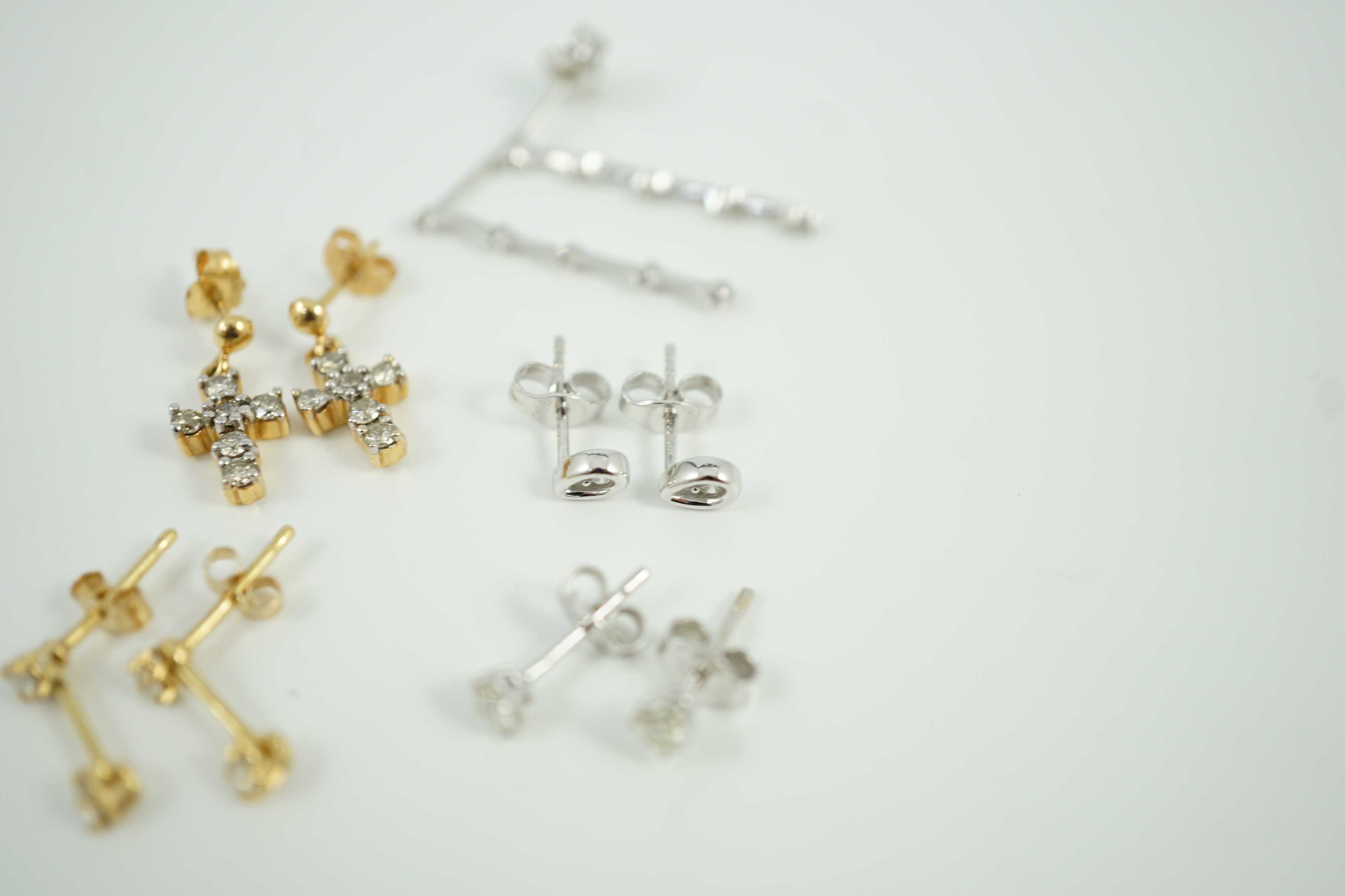 Three pairs of 18ct white gold and diamond set ear rings, including solitaire ear studs and two other pairs of 18ct gold and diamond set ear studs including cross, largest 24mm, gross weight 6.4 grams.